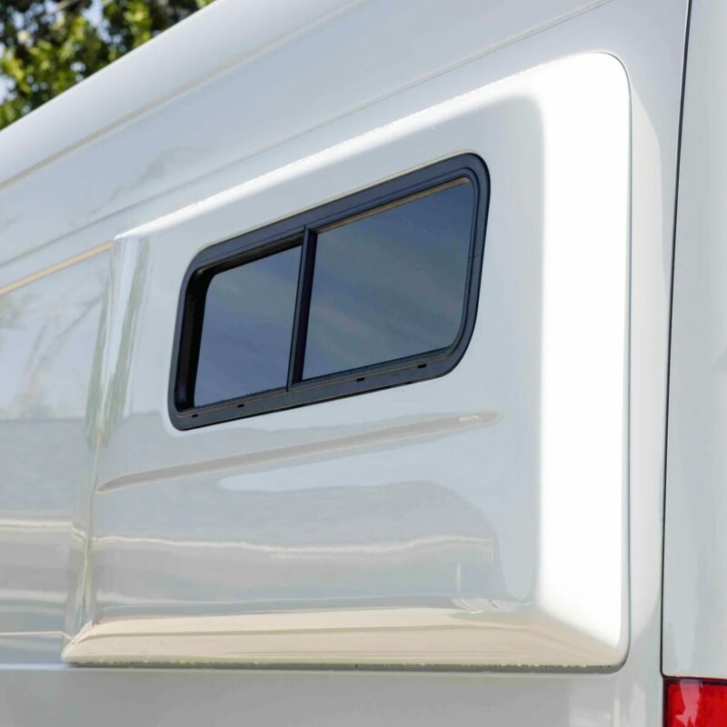 A close-up view of a Flarespace van flare installed on the side of a van. The flare has a window, allowing light into the interior. The rounded, tapered design of the Flarespace flare is visible.