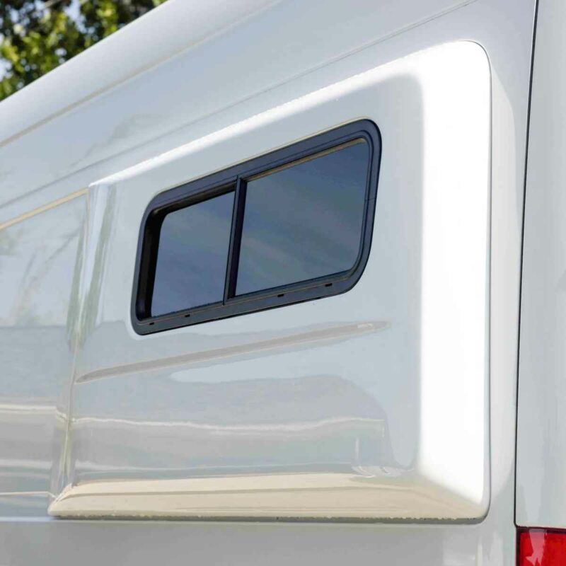 A close-up view of a Flarespace van flare installed on the side of a van. The flare has a window, allowing light into the interior. The rounded, tapered design of the Flarespace flare is visible.