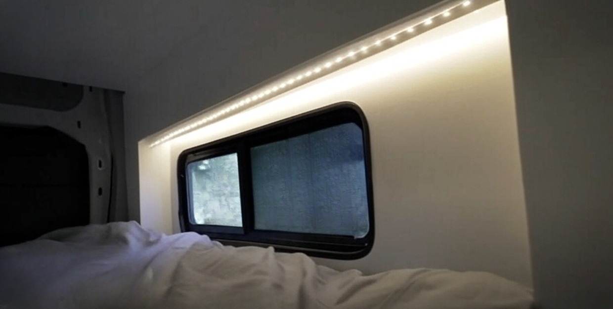 Fully trimmed and finished internal bump-out with installed window in camper van interior.